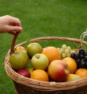 Persona llenando una cesta con fruta fresca conservada en una botella después del proceso de jardinería y riego sin preocupaciones.